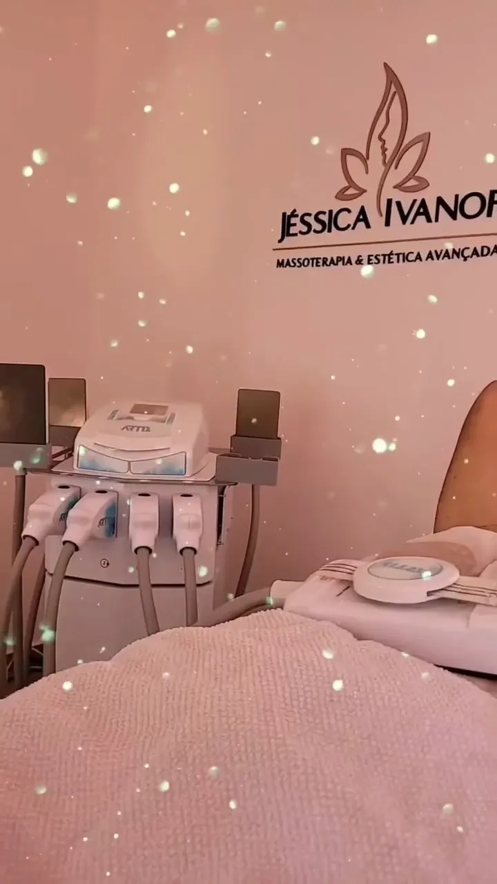 A sala de atendimento na luz rosa, com os aparelhos de crio de placas ao lado da maca e o logo da Jéssica Ivanof na parede